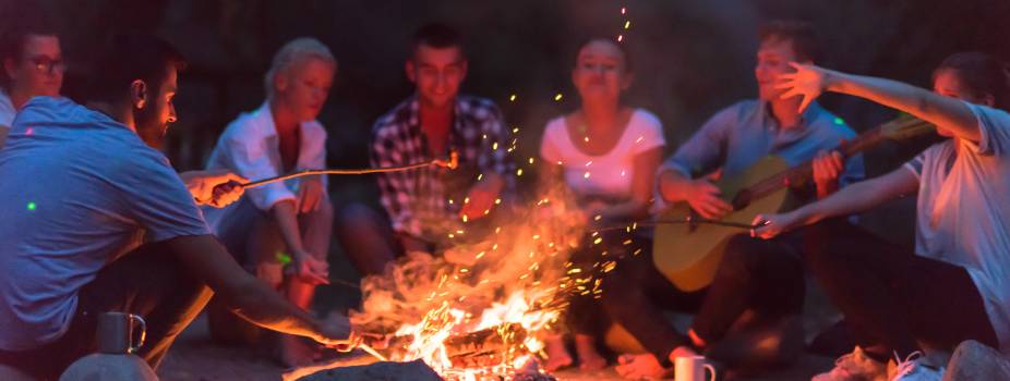 people around campfire wood camping glamping